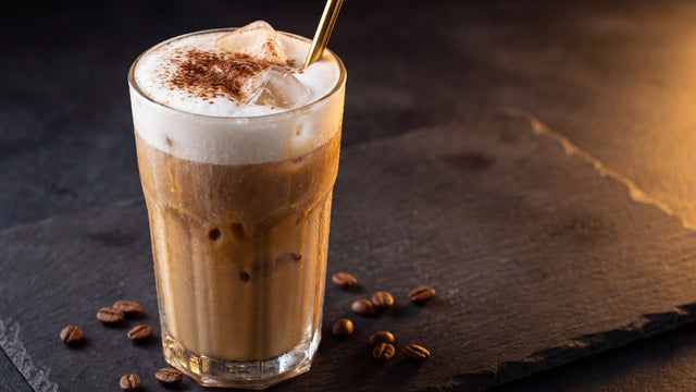 Hohes Glas Protein-Eiskaffee mit cremigem Milchschaum, Kakao und Eiswürfeln auf dunklem Schiefer